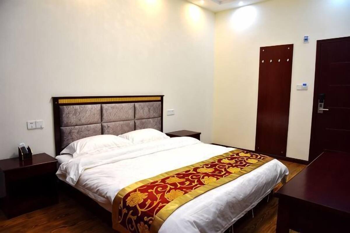 A hotel room with a bed, bedside tables, a wardrobe, and a door.