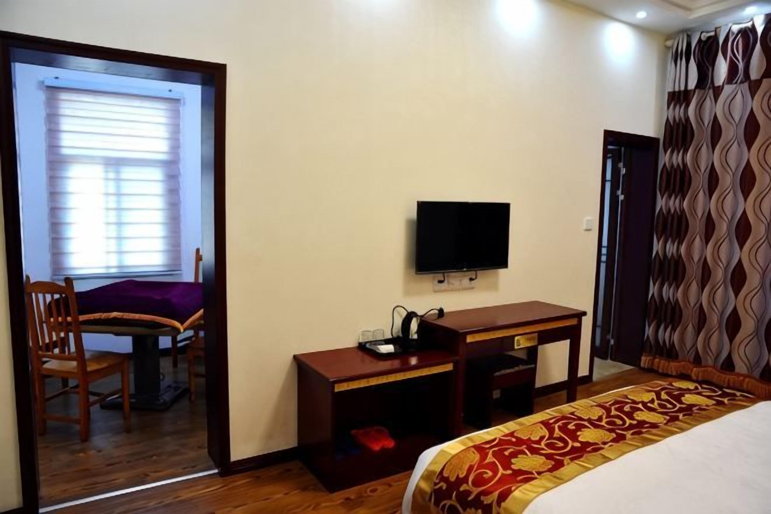 A hotel room with a bed, a desk, a chair, a television, and a door.
