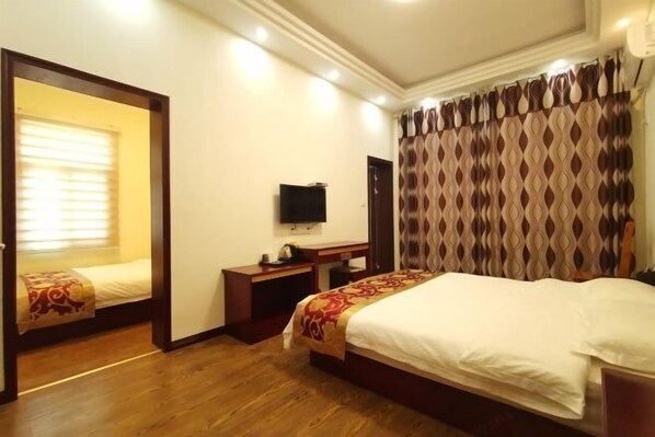 A hotel room with a bed, a desk, a television, and a mirror. - Qianyi Inn (Yichang)