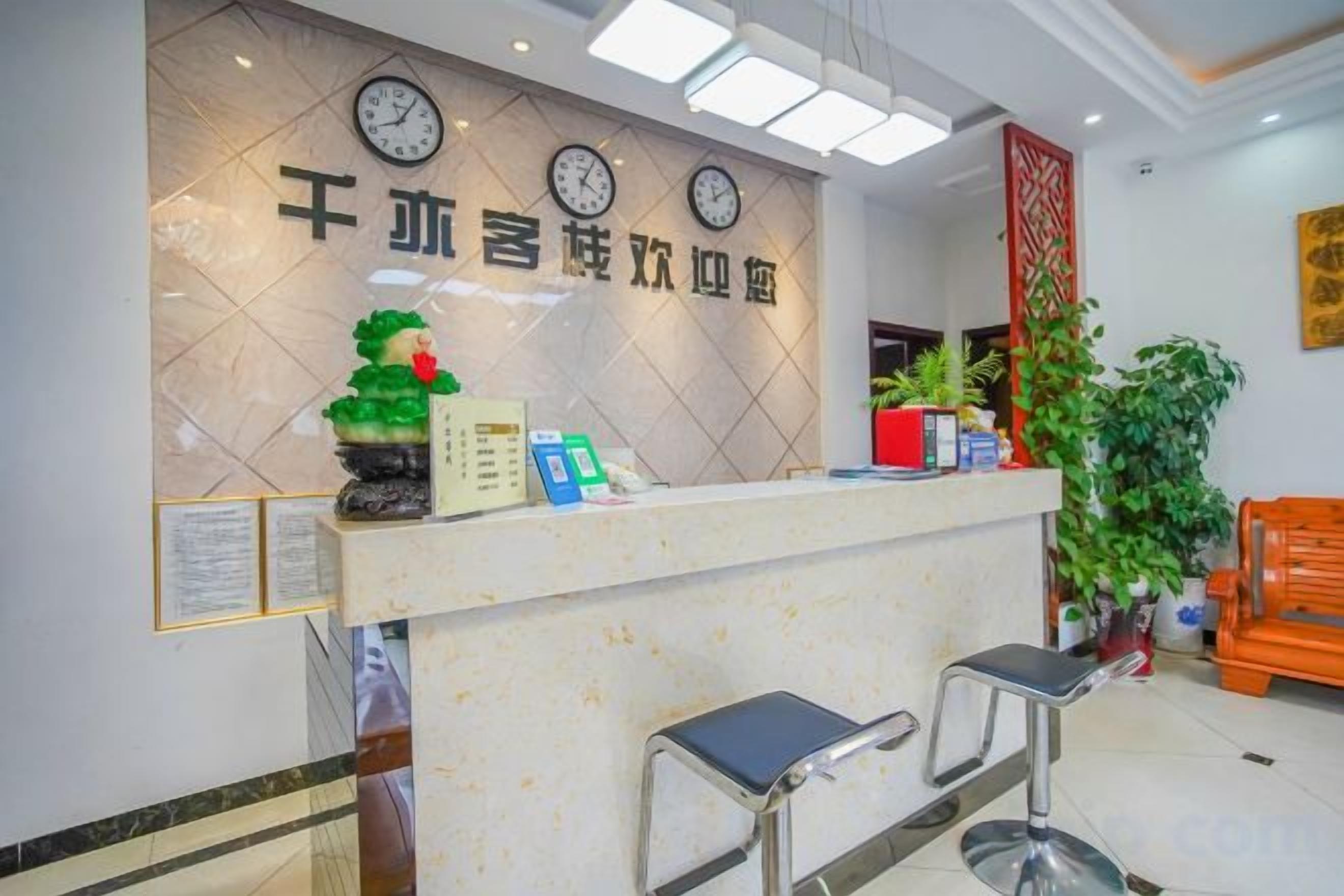 A reception desk with clocks, a plant, and a red pillar.