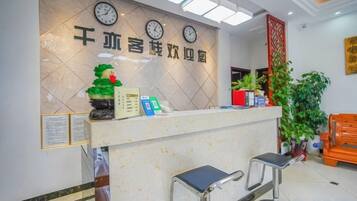 A reception desk with clocks, a plant, and a red pillar.