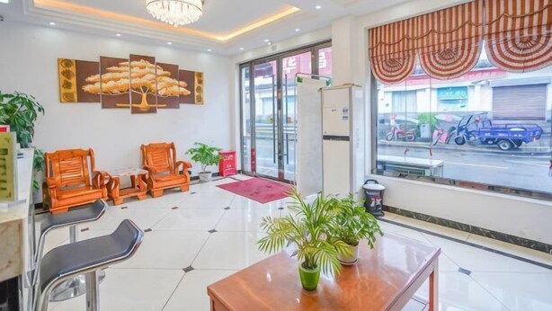 A hotel lobby with a chandelier, wooden chairs, a table with a plant, and a large window with curtains. - Qianyi Inn (Yichang)