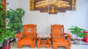 A room with two wooden chairs, a small table, and a wall-mounted painting of a tree. - Qianyi Inn (Yichang)