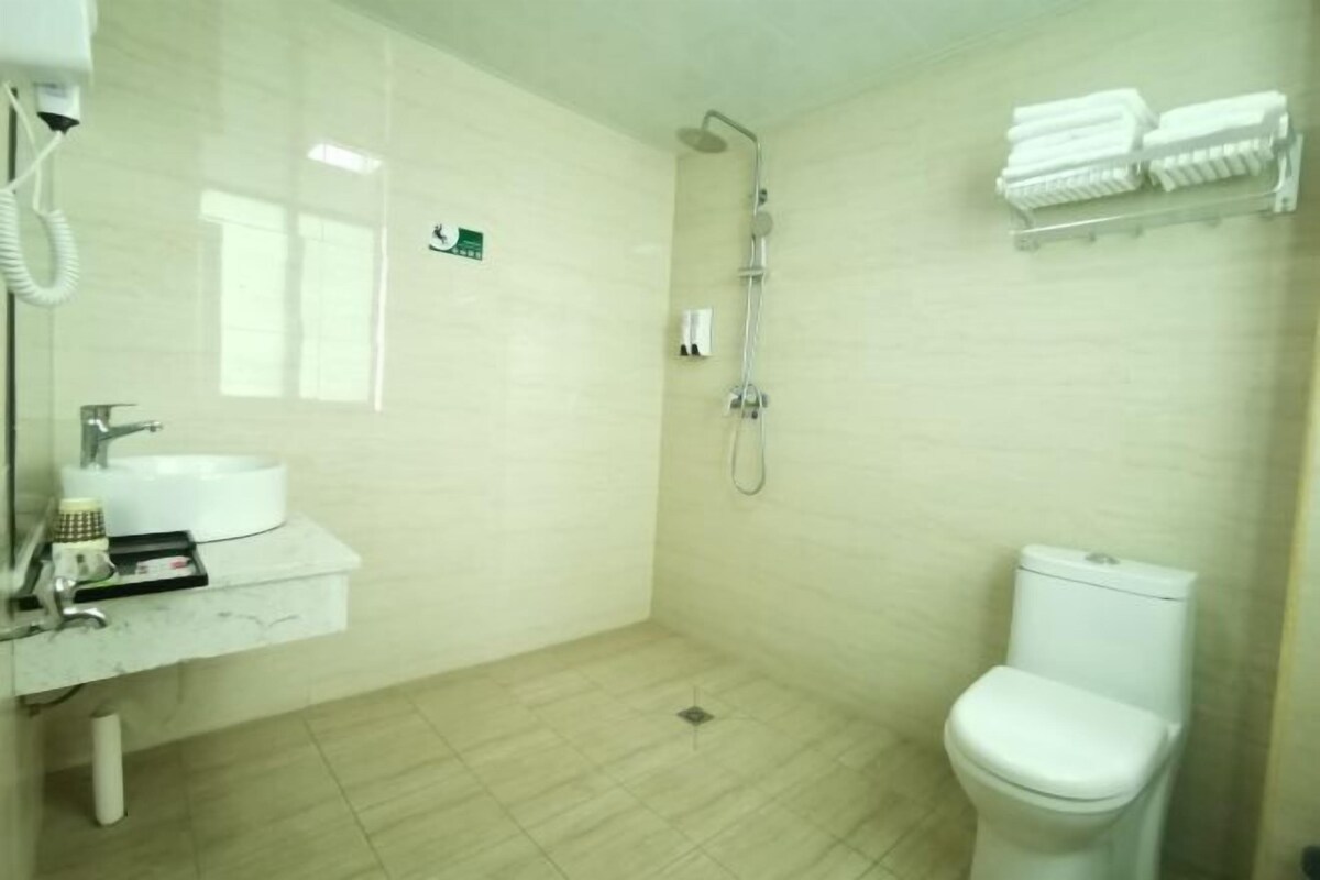 A bathroom with a sink, mirror, shower, and toilet.