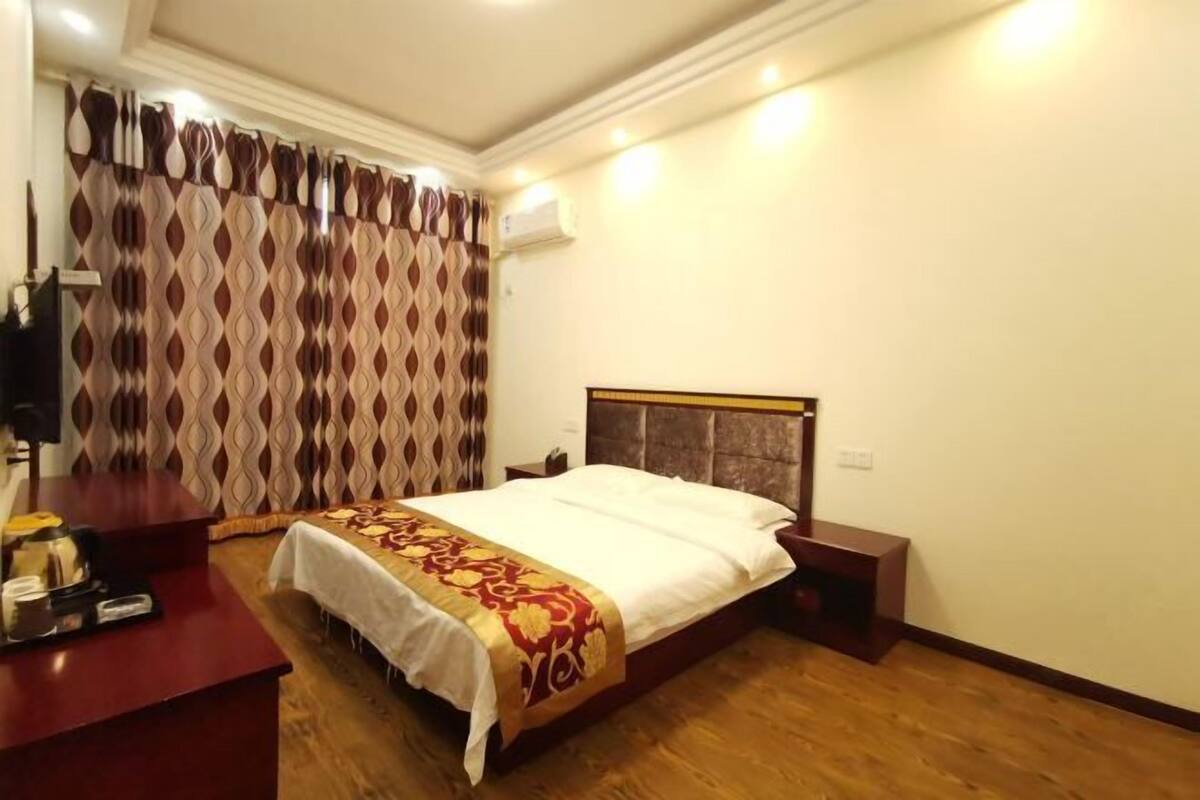 A hotel room with a bed, bedside table, and a desk with a chair.