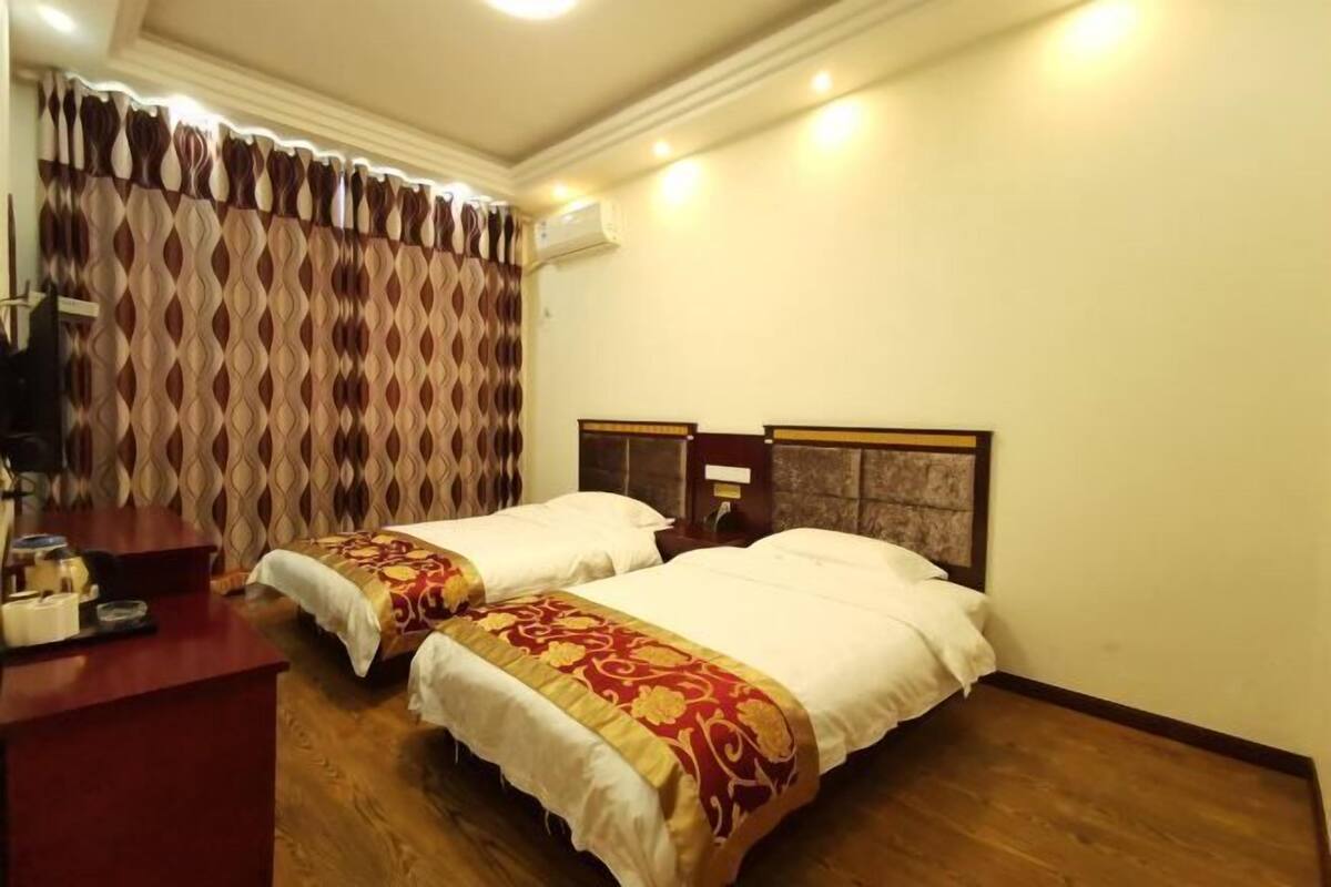A hotel room with two beds, a desk, and a patterned curtain.