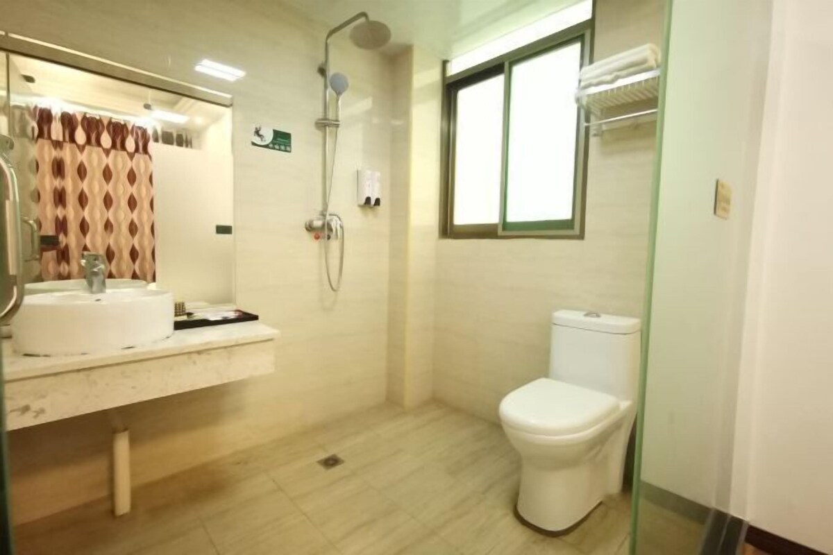 A bathroom with a toilet, shower, and sink.