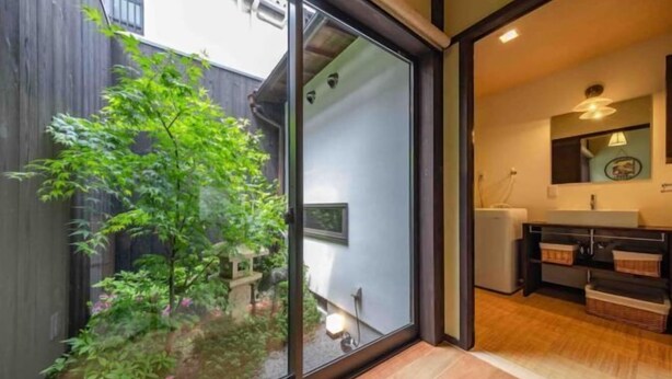 A modern kitchen with a wooden countertop, a sink, and a window overlooking a garden. - Kyoto 11 Inn Shimabara (Kyoto)