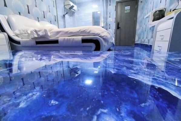 A room with a bed, a mirror, and a door.