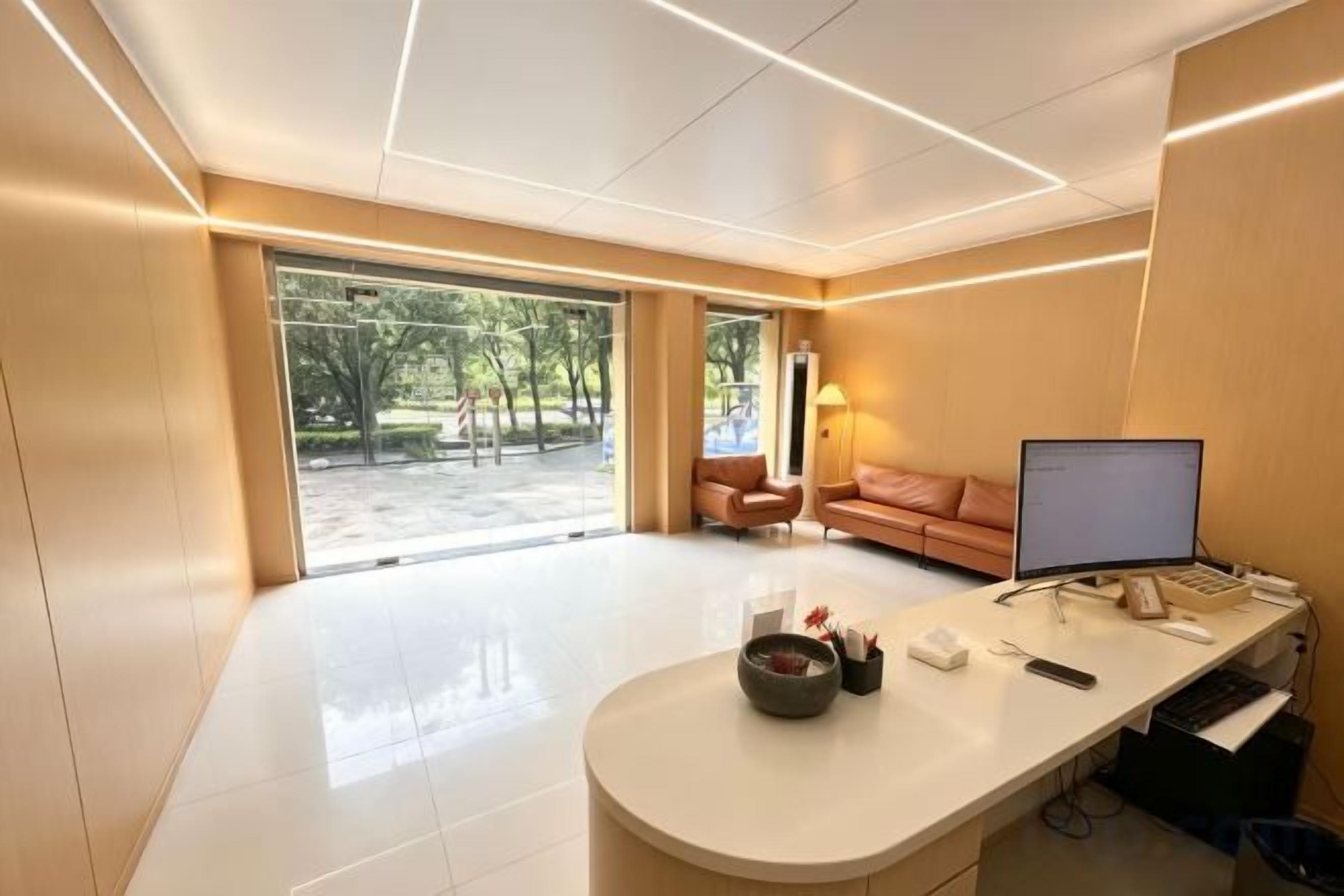 A modern office space with a desk, computer, and a view of the outdoors.