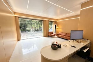 A modern office space with a desk, computer, and a view of the outdoors.