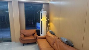 Una habitación con un sofá de cuero marrón, un sillón pequeño y un radiador.