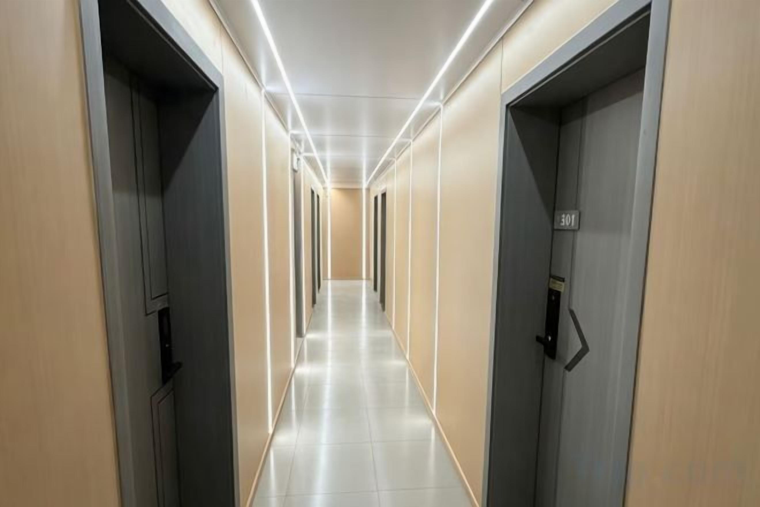 A corridor with doors on both sides, leading to rooms.