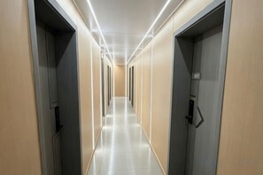 A corridor with doors on both sides, leading to rooms.