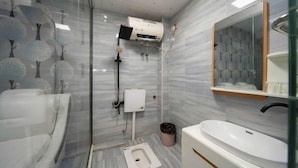 Un baño moderno con cabina de ducha de vidrio, inodoro, lavabo y espejo.