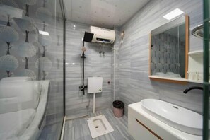 A modern bathroom with a glass shower enclosure, a toilet, a sink, and a mirror. - Yunxuan Hotel Zhangzhou (Chenzhou)