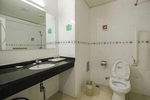 A bathroom with a sink, mirror, toilet, and a trash bin. - Shanhai Holiday Resort (Haikou)