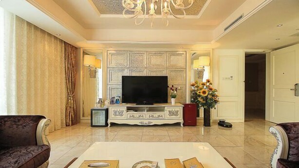 A spacious living room with a flat-screen TV, a coffee table with decorative items, and two sofas. - Shanhai Holiday Resort (Haikou)