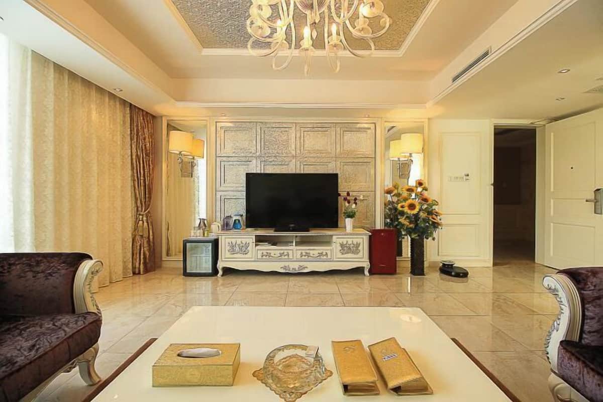 A spacious living room with a flat-screen TV, a coffee table with decorative items, and two sofas.