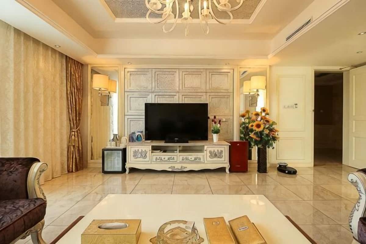 A living room with a television, decorative items, and a chandelier.