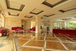 A spacious lobby with a polished wooden floor, red seating, and a large mirror reflecting the room. - Shanhai Holiday Resort (Haikou)