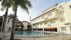 A hotel with a swimming pool, palm trees, and a tiled patio area. - Shanhai Holiday Resort (Haikou)