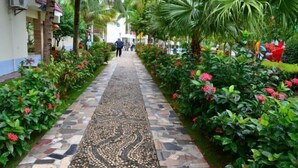 A pathway lined with colorful flowers and a mosaic design, leading to a building with a red roof. - Shanhai Holiday Resort (Haikou)