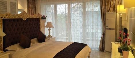 Un dormitorio con una cama grande, una mesita de noche, una lámpara, un aparador y una ventana con cortinas.