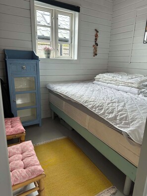 A bedroom with a bed, a small wooden stool, a yellow rug, and a blue cabinet. - Holiday home close to the beach and restaurants (Karrebæksminde)