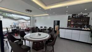 Un ristorante moderno con tavoli rotondi, sedie nere, una zona bar e vista su un edificio esterno.