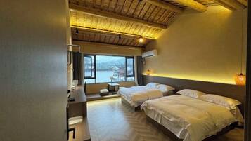 Habitación de hotel con dos camas, un escritorio, una silla, un ventanal con vistas y techo de madera.