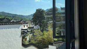 Un edificio tradizionale con tetto in tegole, immerso nel verde e con montagne sullo sfondo.