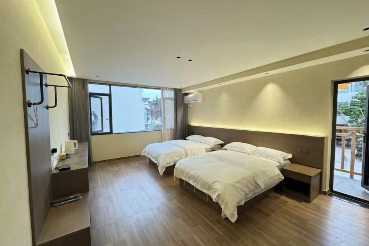 Una habitación de hotel moderna con dos camas, un escritorio, una silla y un ventanal grande.