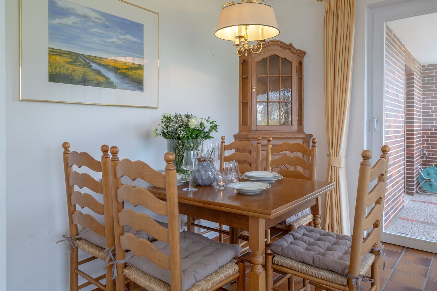 Un coin repas comprenant une table en bois, des chaises, un buffet et une lampe.