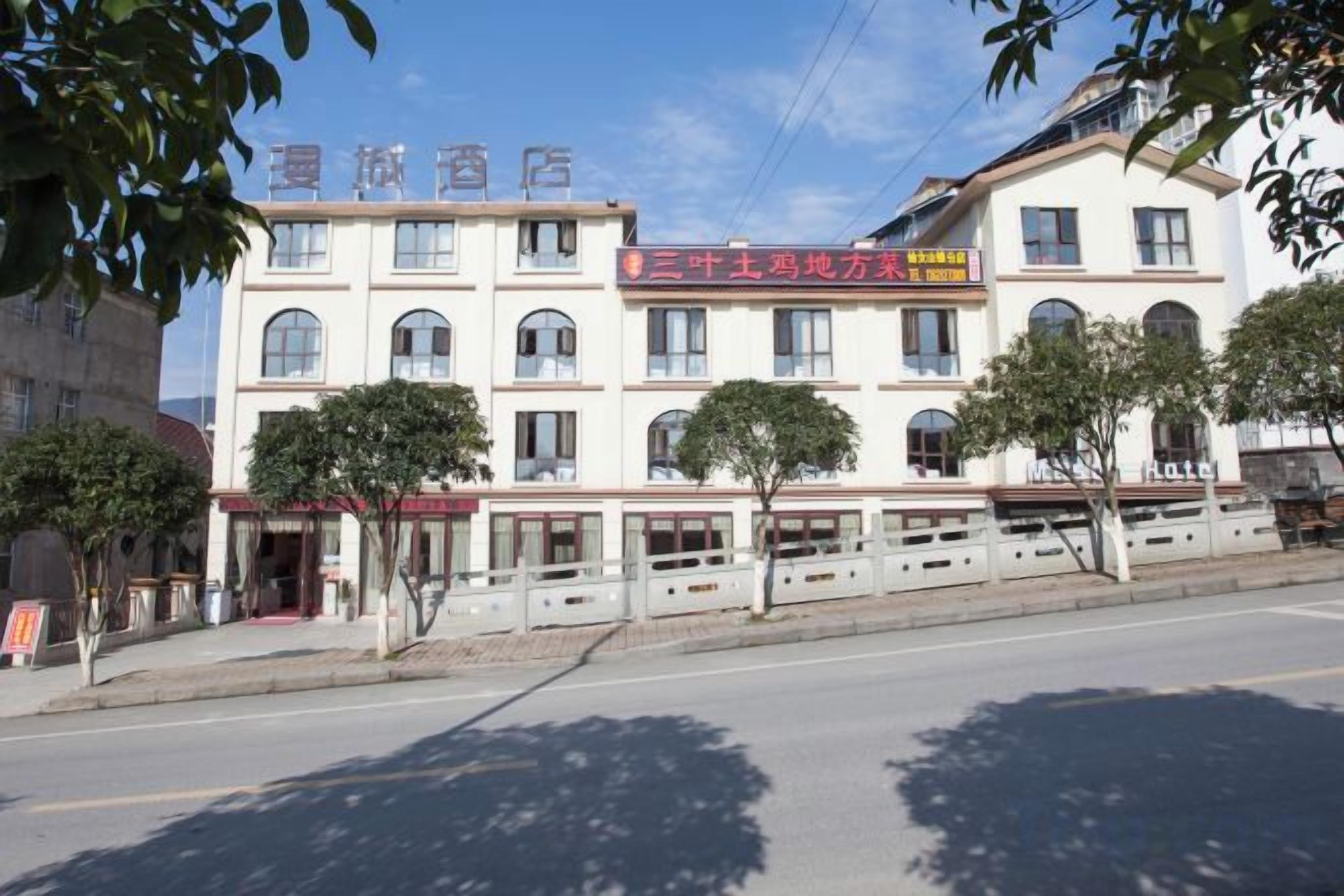A multi-story hotel with a red signboard, multiple windows, and a tree-lined facade.