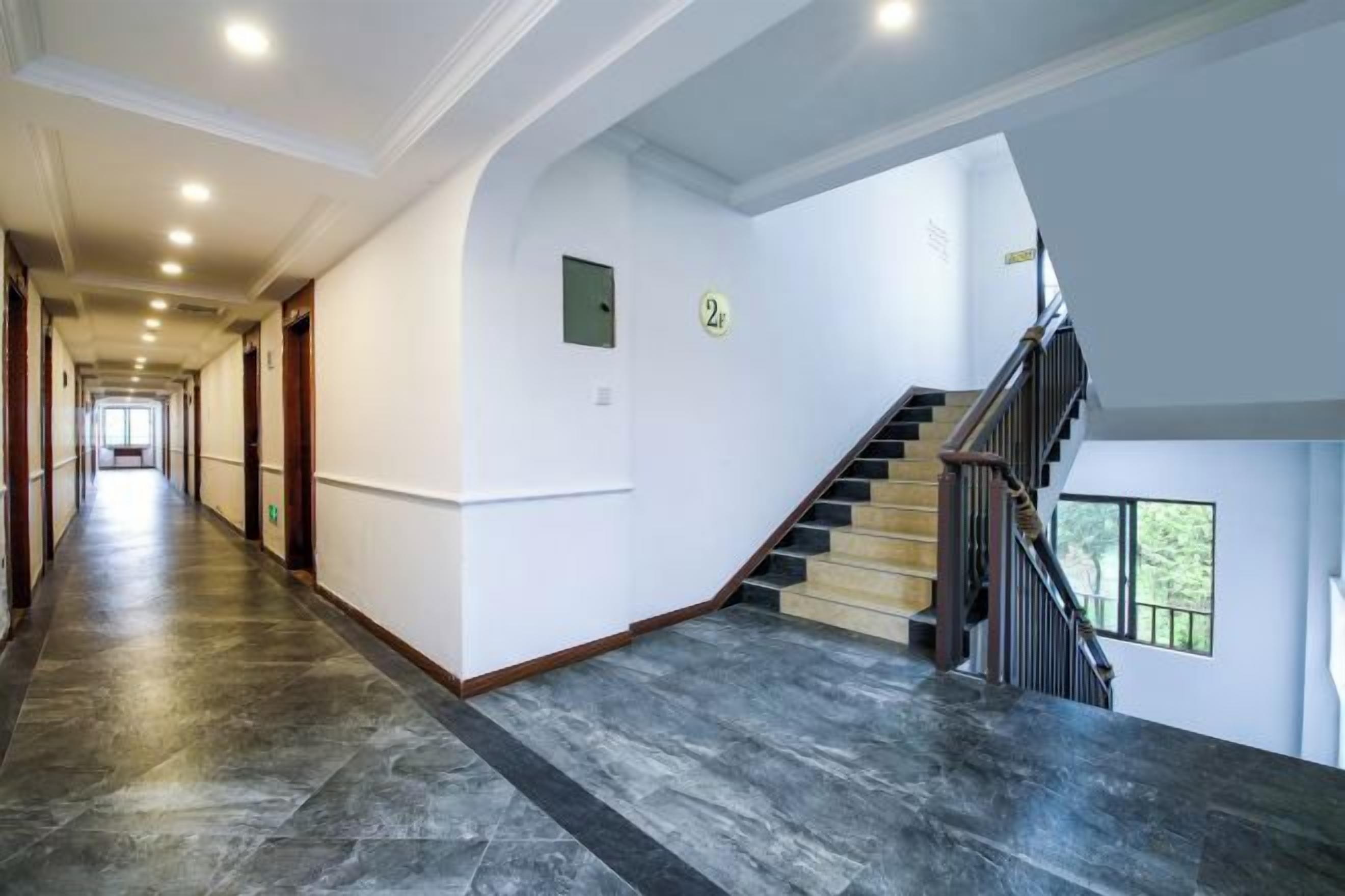 A spacious hallway with a staircase leading to an upper floor, featuring a marble floor and a modern design.