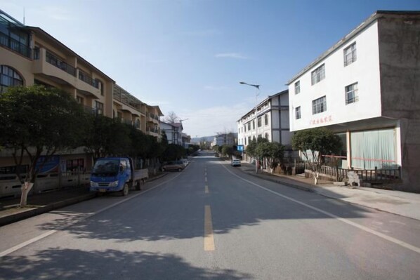 A street with buildings on both sides, a clear sky, and a van parked on the left. - Mason Hotel (Chongqing)