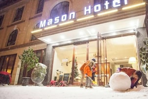 Exterior do Mason Hotel com entrada coberta de neve e decoração de árvore de Natal.