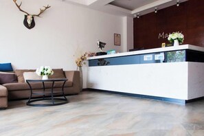 A reception area with a reception desk, a sofa, a coffee table, and a wall-mounted deer skull. - Mason Hotel (Chongqing)