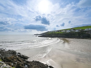 Enjoy the serene coastal landscape with gentle waves lapping onto the shore.