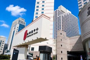 A hotel entrance with a prominent sign, tall buildings in the background, and a clear blue sky. - Ningbo Boteman Apartment (Ningbo)