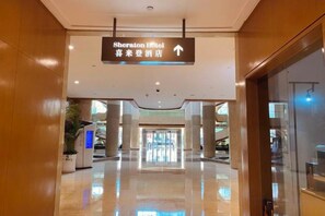 A hotel corridor with a sign for the Sheraton Hotel, a polished floor, and a glass door on the right. - Ningbo Boteman Apartment (Ningbo)