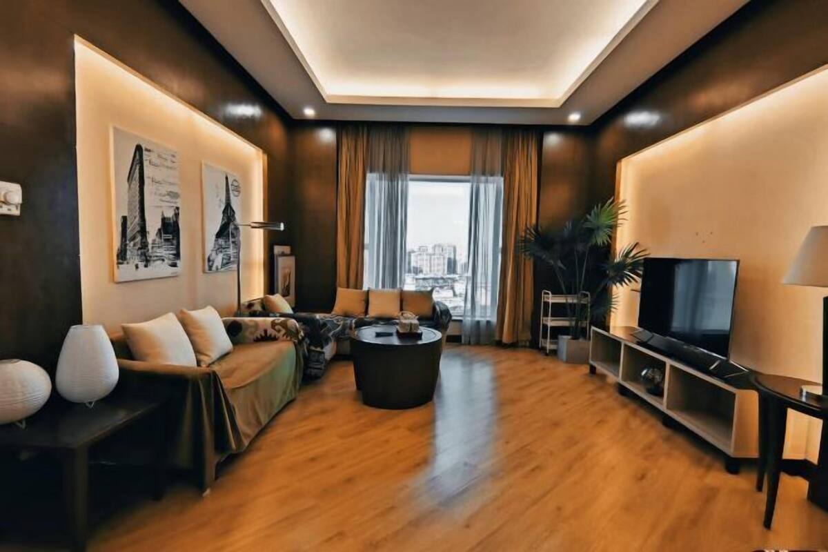 A modern living room with a sofa set, a coffee table, a TV, and artwork on the walls.