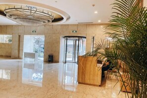 A hotel lobby with a reception desk, a revolving door, and a large chandelier. - Ningbo Boteman Apartment (Ningbo)