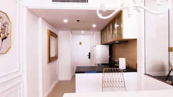 A modern kitchen with white cabinetry, a black countertop, and a chandelier.