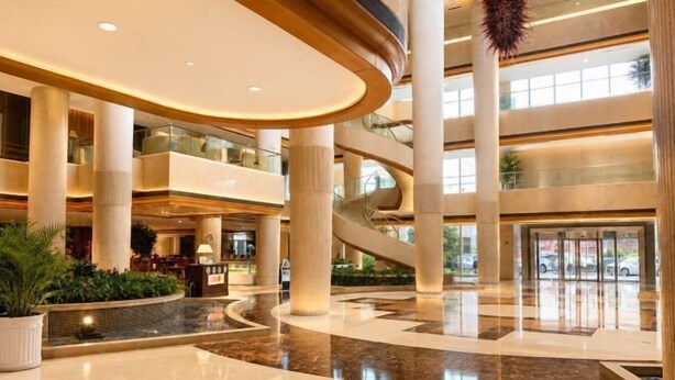 A multi-level atrium with a central staircase, large columns, and a reflective floor. - Ningbo Boteman Apartment (Ningbo)