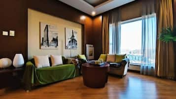 A modern living room with a green sofa, a brown coffee table, and a large window with curtains.