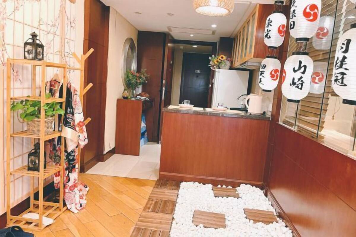 A hotel lobby with a wooden reception desk, a plant, and traditional Japanese lanterns.