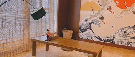 Une pièce comprenant un banc en bois, une petite table, une lampe suspendue et une fresque murale de style japonais traditionnel.