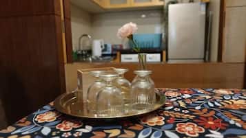 A tray with four glass vases and a single pink flower on a patterned tablecloth.